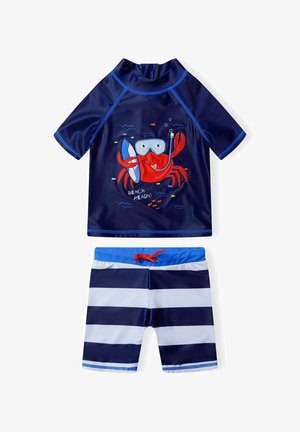 Tamsiai mėlynas maudymosi kostiumėlis, kurį sudaro trumpomis rankovėmis marškinėliai su krabų piešiniu ir derančios juostuotos šortai. Pagamintas iš greitai džiūstančios, lengvos medžiagos.