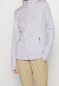Giacca zip-up di un delicato viola chiaro con colletto alto, tessuto testurizzato e due tasche laterali con cerniere in tono argento.