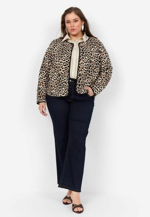 Leopard print quilted jacket with black trim, beige button-up shirt, navy high-waisted jeans, and patterned sandals. Large hoop earrings.