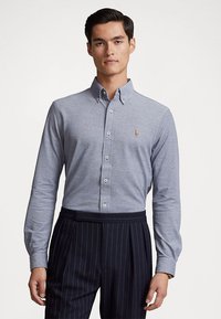 Lichtblauw overhemd van een katoenmix met lange mouwen, voorzien van een klein geborduurd logo en witte knopen, gecombineerd met gestreepte broeken.