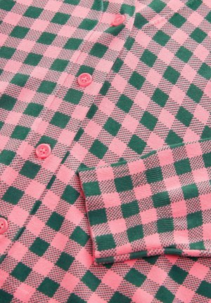 Chemise à carreaux rose et verte en tissu tricoté, avec des boutons contrastants et un col rabattu à finition texturée.