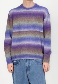 Pull en maille avec des rayures horizontales dans des tons violet, bleu et marron. Confectionné dans un matériau doux avec un col rond et des poignets côtelés.