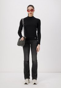 Black long-sleeve fitted top, dark gray flared jeans, gray shoulder bag, cream sneakers, and red sunglasses. Simple, modern design.