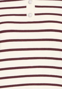 Tissu tricoté couleur crème avec des rayures horizontales marron foncé et deux boutons en strass scintillants près du centre supérieur.