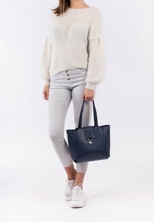 Sac fourre-tout bleu marine avec une forme structurée, finition brillante, doubles poignées et un accent décoratif en forme d'anneau à l'avant. Tissu : synthétique.