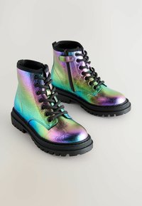Bottes holographiques à lacets avec des accents noirs, équipées d'une fermeture éclair sur le côté et d'une semelle en caoutchouc épaisse avec un motif texturé pour une meilleure adhérence.