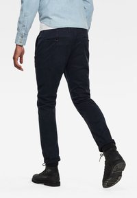 Navy cottonblandbyxor med slim fit, dragkedje- och knappstängning, två bakfickor och uppvikta cuffs, i kombination med svarta snörkängor.