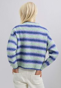 Cardigans a rayas en azul claro, verde y púrpura. Textura suave con dobladillo acanalado y corte relajado. Presenta mangas largas y cuello.