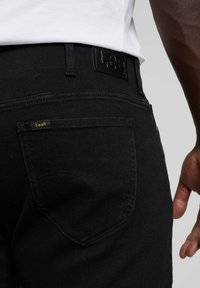 Czarne dżinsy z efektem struktury, z widoczną łatką logo Lee® na talii oraz zakrzywionymi tylnymi kieszeniami z detalicznym przeszyciem.