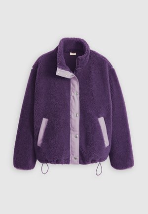 Jaqueta de lã polar roxa com colarinho alto, fechos de pressão, bolsos lilases contrastantes e cordão ajustável na bainha para um ajuste personalizado.