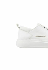 Sneaker bianco in pelle con punta arrotondata, suola rialzata e una linguetta sul tallone. Presenta un logo discreto in oro di lato.