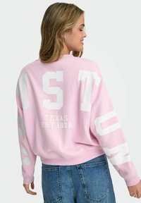 Roosa dressipluus valgete plokk-kirjadega "HOUSTON" ja "TEXAS EST 1876" seljal. Omaduseks mugav lõige ja soonikkoes mansetid.