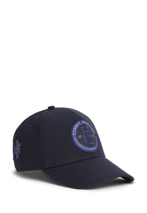 Granatowa czapka bejsbolowa z okrągłą naszywką Tommy Hilfiger przedstawiającą żaglówkę i napis „Authentic Ocean” na przednim panelu.