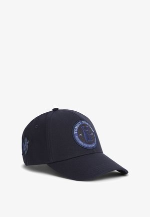 Granatowa czapka bejsbolowa z okrągłą naszywką Tommy Hilfiger przedstawiającą żaglówkę i napis „Authentic Ocean” na przednim panelu.