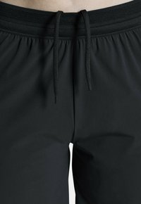 Zwarte sportshorts met een elastische tailleband en een gestructureerde band, verstelbare trekkoorden en een gladde matte stof.