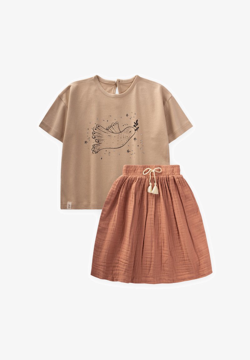 Beige Baumwoll-T-Shirt mit einem schwarzen Taubenmotiv, kombiniert mit einem strukturierten rockfarbenen Rock mit elastischem Bund und Quastendetails.