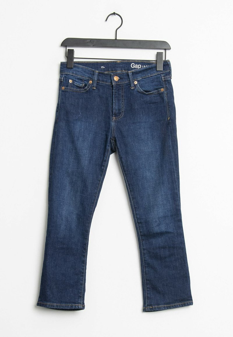 Jean en denim bleu foncé avec un design à cinq poches, coupe droite, rivets en cuivre et coutures beiges. Suspendu à un cintre en plastique noir.