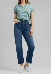 Stribet teal og hvid v-neck t-shirt parret med højtaljede blå jeans og hvide sneakers. Afslappet fit; casual design.