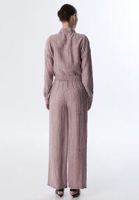 Completo a due pezzi di colore viola chiaro, con texture, composto da una camicia con maniche lunghe e bottoni e da pantaloni larghi con vita elastica.