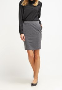 Grijze kokerrok tot de knie met een gladde textuur, gecombineerd met een zwarte knopsluiting shirt met lange mouwen. De rok heeft een aansluitende tailleband.