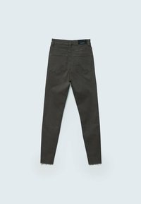 Pantalones vaqueros ajustados de color verde oscuro con dobladillo deshilachado, dos bolsillos traseros y textura suave. Etiqueta visible en la cintura.