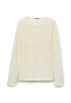 Blouse en dentelle crème à manches longues avec un motif floral et un col rond, présentée à plat sur un fond blanc.
