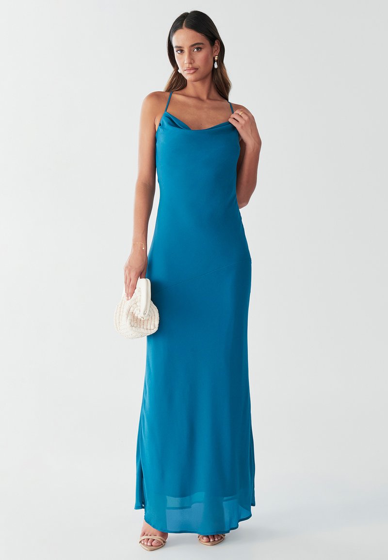 Turkizna satenska maxi obleka z drapiranim vratnim delom in tankimi naramnicami. Ima stranski razporek in je kombinirana s kremasto torbico z teksturo.