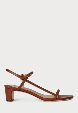 Sandale en cuir marron avec un petit talon bloc, fines brides dont une autour de la cheville avec une petite boucle dorée.