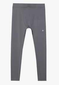 Pilki sportiniai leggingai, pagaminti iš elastingos medžiagos, pasižymintys prigludusia forma, elastingu juosmeniu ir maža logo esančia arti apačios.