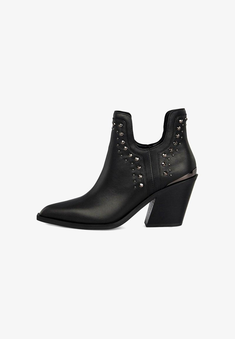 Czarny botek za kostkę z wąskim noskiem, wykonany z gładkiej skóry. Ozdobiony metalicznymi ćwiekami i grubym obcasem. Posiada wycięty wzór.