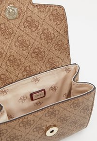 Lysebrun tekstureret stofpung med subtilt prægede mønster og metallisk trykknaplukning. Interiøret har en lys foring med gentaget logo-detalje.