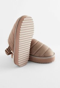 Chaussures confort en cuir suédé marron avec un design matelassé, semelle en caoutchouc texturé et doublure douce, présentant un détail de dos froncé.