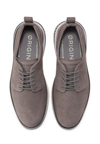 Grå mockaskor med perforerad detaljering, platta grå snörningar och en kontrasterande mönstrad innersula. Designade för komfort med en gummisula.