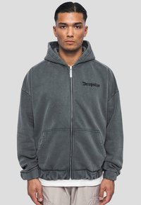 Sivi zip-up dukserica napravljena od mekog flisa. Ima prednji džep i crni natpis "Dropsize" na lijevoj strani prsa.