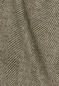 Tejido con patrón de espiga en tonos verdes terrosos y beige, hecho de lana suave y texturizada, que presenta rayas diagonales y un aspecto cálido.