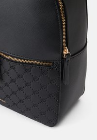Mochila preta com um acabamento texturizado e fecho dourado. Apresenta um bolso frontal com um padrão floral em relevo e um design elegante.