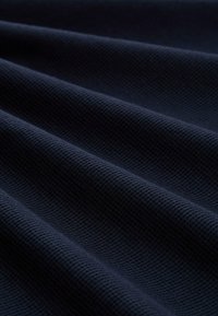 Granatowa tkanina o fakturze z żeberkowanym wzorem, prezentująca pionowe fałdy i miękkie wykończenie, odpowiednia do odzieży lub tapicerki.