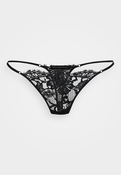 String noir en dentelle avec un motif floral, des panneaux transparents et de fines bretelles élastiques. Présente de petites accents en matériel circulaire. Texture lisse.