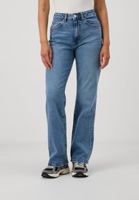 Jeans de denim azul de cintura alta com um corte reto, textura desbotada, costura visível e design clássico de cinco bolsos.