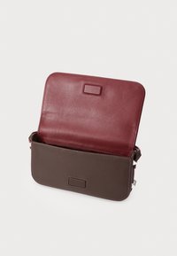 Borsa in pelle con patta bordeaux e corpo marrone. Presenta una texture liscia, una forma rettangolare e un dettaglio frontale a linguetta. Interno aperto.