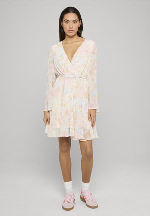 Abito a portafoglio floreale con maniche lunghe, colori pastello, tessuto leggero, vita aderente, gonna a balze, abbinato a sneakers rosa e calzini bianchi.