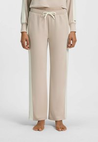 Beige sweatpants met crèmekleurige zijstrepen, voorzien van een elastische tailleband en een trekkoord. Gemaakt van zachte stof, met een ontspannen pasvorm.