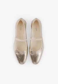 Metallic gold ballet flats with a round toe, elastic strap, smooth leather texture, and a subtle sheen, featuring a minimalist design.