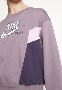 Lila Nike sweatshirt med färgblockering som har ljusrosa och mörklila paneler. Material i bomullsblandning, rund halsringning och logotypdetalj.