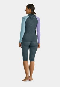 Activewear set featuring a hooded top with color-blocked blue and purple sleeves, paired with fitted, dark leggings. Smooth fabric texture.