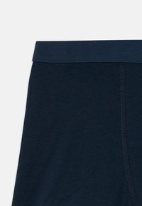 Marineblaues Bündchen und oberer Abschnitt der Unterwäsche aus weichem Baumwollstoff mit sichtbaren Nähten auf weißem Hintergrund.
