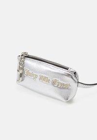 Silverfärgad metallisk liten påse med texturerad yta, som har texten "Juicy Me Trust" i guldfärgade bokstäver och en silverkedja som dragkedja för stängning.