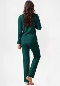 Set di pigiami in raso teal con top a maniche lunghe e pantaloni a lunghezza intera. Tessuto liscio e vestibilità comoda, con design semplice e senza decorazioni visibili.