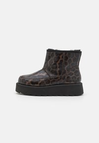 Botas de tobillo con estampado de leopardo negro y marrón, fabricadas con un material brillante, suela plana y gruesa de color negro y un suave forro de piel alrededor del borde superior.