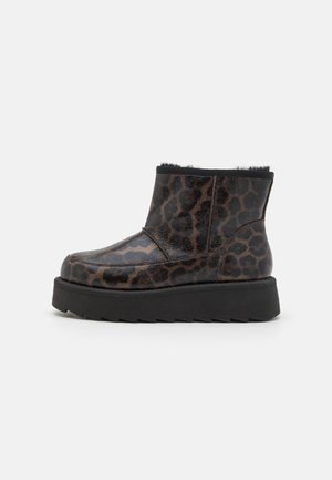 Bottines à imprimé léopard noir et brun en matériau brillant, avec une semelle plate et épaisse noire et un revêtement en fourrure douce autour du bord supérieur.